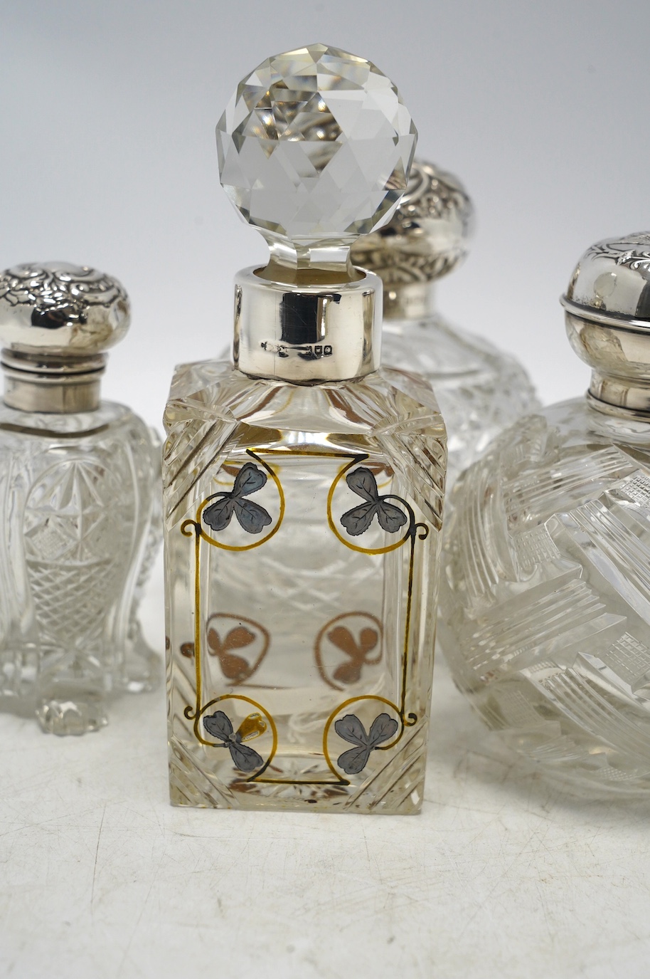 Four assorted early 20th century silver mounted glass scent bottles, tallest 16.1cm. Condition - fair